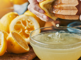 Käega pressitakse värsket sidrunimahla puidust pressiga klaaskaussi