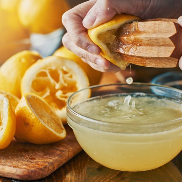 Käega pressitakse värsket sidrunimahla puidust pressiga klaaskaussi