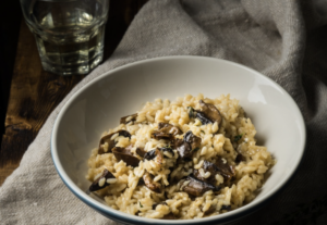 Vegan risoto shiitake seente ja valge mandlivõikreemiga taldrikul, kaunistatud värske peterselliga