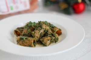 Punase läätse ja riisi pasta musta lehtkapsa-pistaatsiapesto ja taimse bešamellikastmega taldrikul.