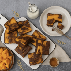 Kõrvitsa-juustukook-brownie viil taldrikul, pehme marmorise mustriga.